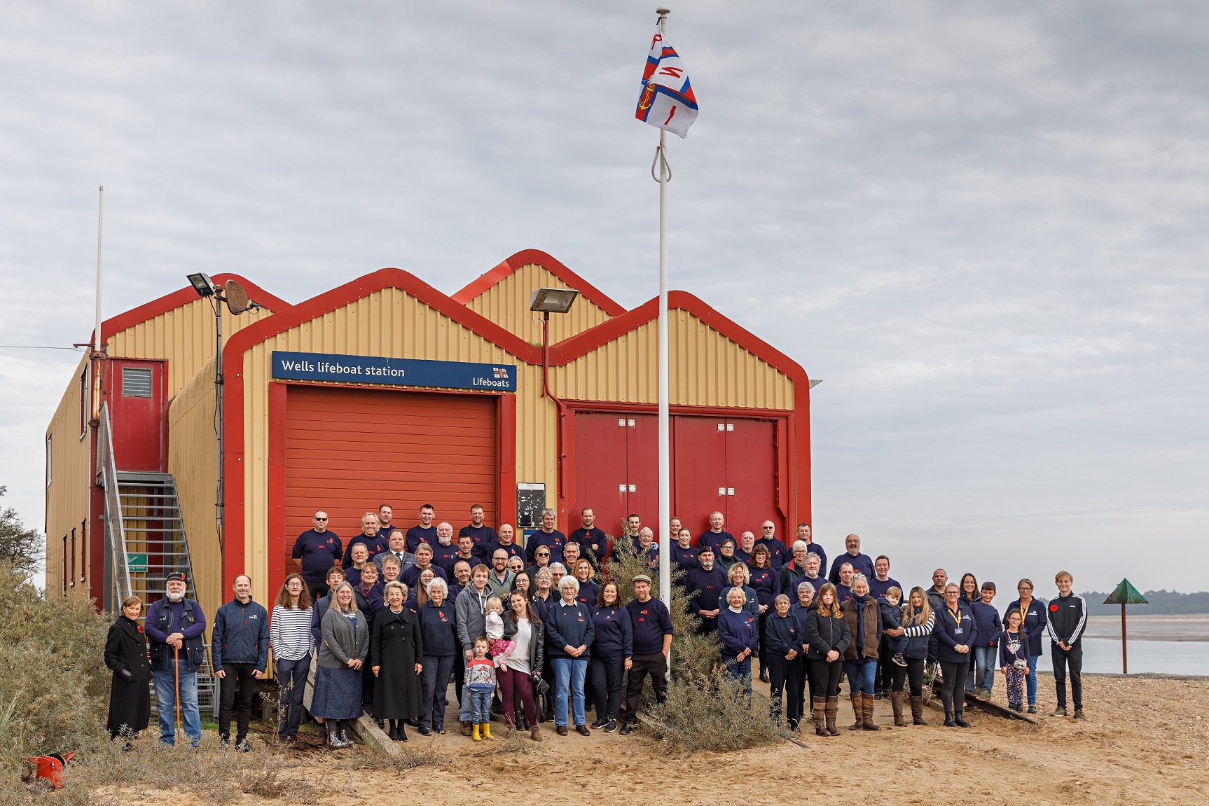 Crew, families and friends outside the old boathouse before the flag is lowered